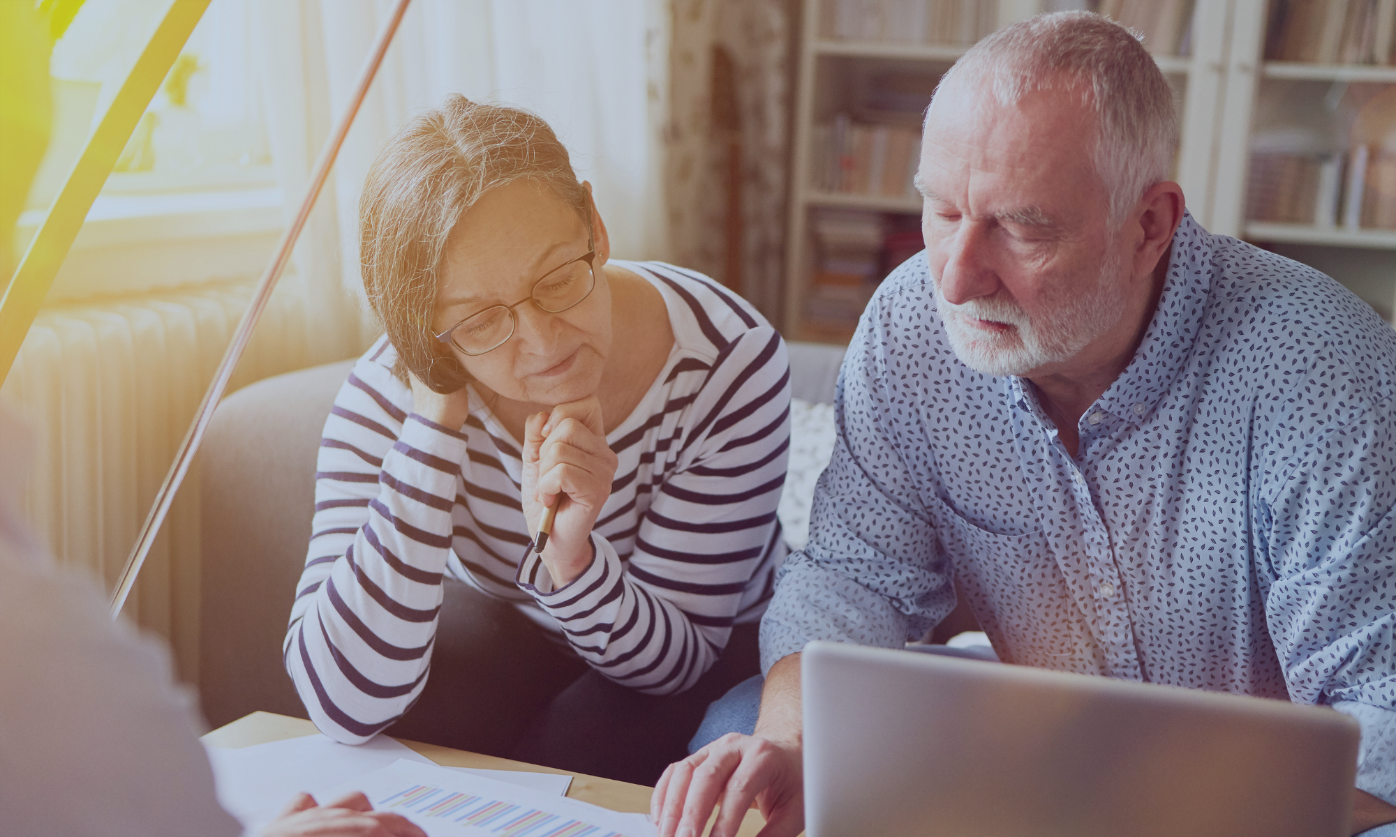 Older couple reviewing financial documents and discussing retirement plans.